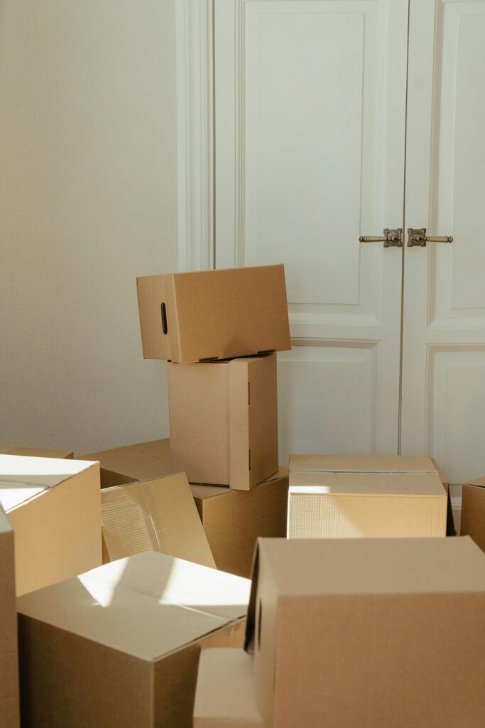 Stack of cardboard boxes by a white wooden door, perfect representation of moving day readiness.